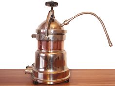 a coffee pot sitting on top of a wooden table next to a metal faucet