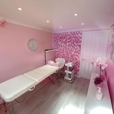 a room with pink walls and white furniture in the corner, along with a large clock on the wall