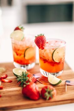 two glasses filled with watermelon and garnish sitting on a wooden table