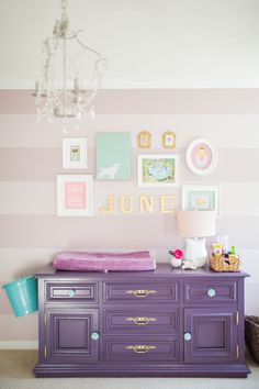 a baby's room with purple furniture and pictures on the wall