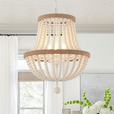 a chandelier hanging from the ceiling in a room with white curtains and flowers