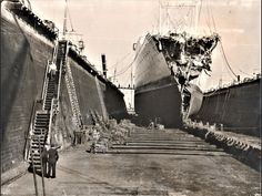 an old black and white photo of people walking up stairs to a large ship in dry dock