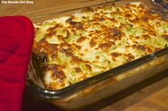 a casserole dish with broccoli and cheese in it on a wooden table