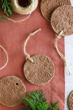 some brown ornaments are on a red table cloth next to twine and sprigs