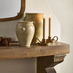 two vases are sitting on a shelf next to a candle holder and mirror in the corner