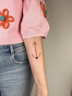 a woman's arm with an anchor and flower tattoo on the left side of her arm