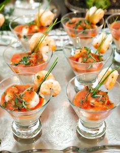 small glass dishes filled with shrimp and garnishes on a silver platter