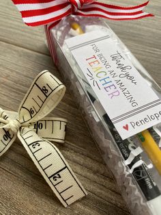 a pencil and ruler wrapped in ribbon sitting next to each other on a wooden table