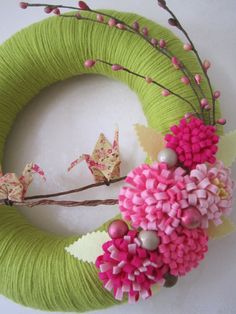 a green wreath with pink flowers and two birds on the front, sitting next to each other