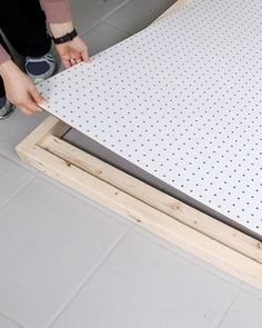 a person standing next to a piece of wood with holes in the bottom and on top