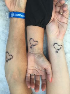 two people holding hands with tattoos on their arms and one has a heart in the middle