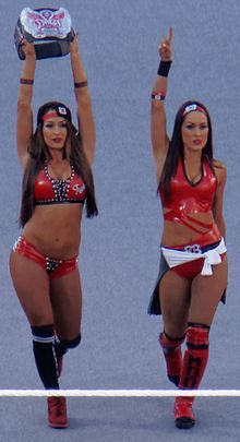 two women dressed in red and black cheer for the camera while holding up their hands