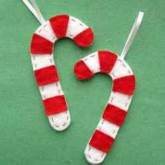 two red and white candy canes hanging on a green surface with one being cut out