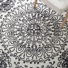 a black and white rug with an intricate design on the floor in front of a chair