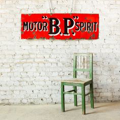 a green chair sitting in front of a red motor b p r t sign on a white brick wall