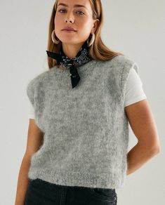 a woman wearing a gray sweater vest and black bow tie