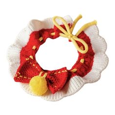 a red and white knitted wreath with yellow bells