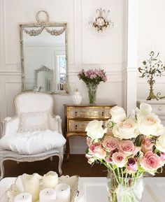 a vase filled with pink roses sitting on top of a table next to a white chair