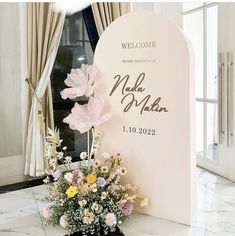 a bouquet of flowers sitting on top of a white table next to a sign that says welcome