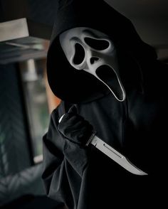 a person wearing a mask and holding a knife in their hand with the hood up