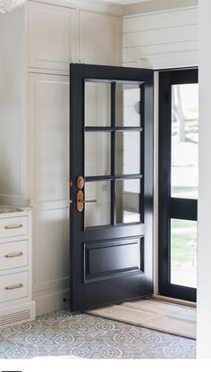 a black door is open in a room with white walls and drawers on either side