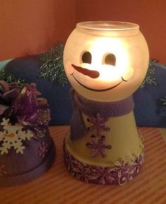 two snowmen sitting on top of a table next to each other with lights in them