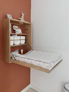 a baby crib hanging from the side of a wall next to a white toilet