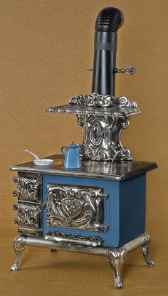 an old fashioned stove is sitting on top of a blue box with silver trimmings