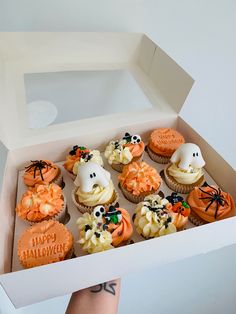 a box filled with cupcakes covered in frosting and decorated to look like ghostes