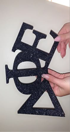 two hands are holding the letter e with glitter on it