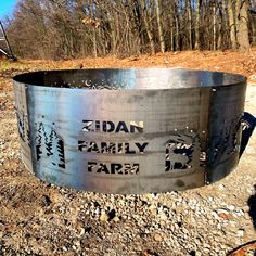 a metal fire pit sitting in the middle of a forest filled with trees and rocks