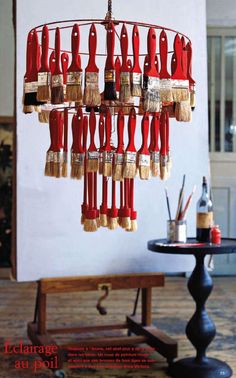 a red chandelier with paint brushes hanging from it