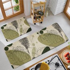 two kitchen mats with leaves on them in front of a stove top and an oven