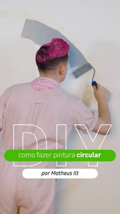 a man with pink hair is painting a white wall and the words diy on it