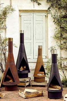 three different types of outdoor fireplaces sitting in front of a building with white doors