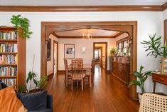 a living room filled with furniture and bookshelves next to a dining room table