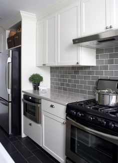 a kitchen with white cabinets, black and silver appliances and tile backsplashes