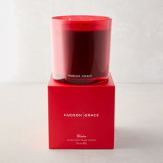 a red candle sitting on top of a box with the words hudson grace in it