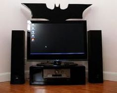 a flat screen tv sitting on top of a wooden floor in front of a batman sign