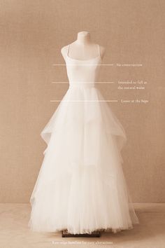 a white dress on display in front of a beige background with words describing the parts of it