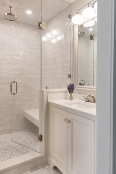 a bathroom with a walk in shower next to a white sink and bathtub under two lights