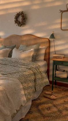 a bed sitting in a bedroom next to a wall mounted mirror and lamp on top of a wooden headboard