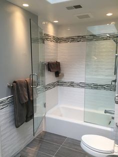 a white toilet sitting next to a bath tub in a bathroom under a skylight