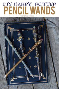 three different types of writing instruments sitting on top of a blue book with gold trimmings