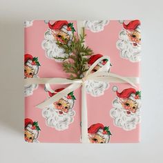 a present wrapped in pink wrapping paper with santa's face and beards on it