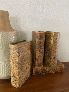 two old books are sitting on a table next to a white vase with a lamp