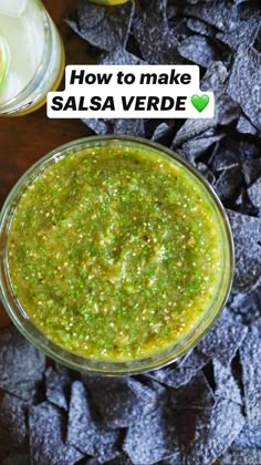 two glasses filled with guacamole and chips on top of a wooden table