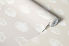 a white wallpaper with clouds on it and a roll of paper next to it