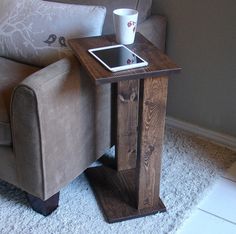 a small wooden table with a tablet on it next to a chair in a living room