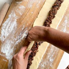 a person is kneading dough on top of a wooden cutting board with a knife